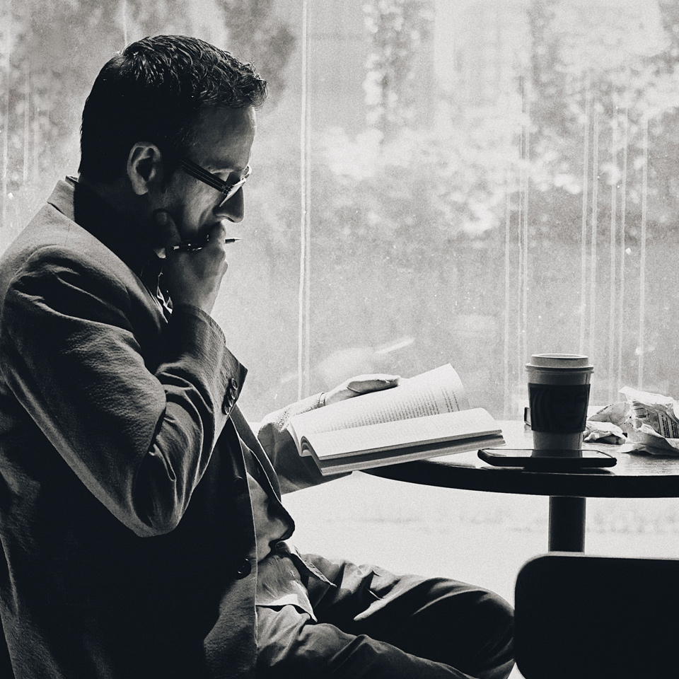 man-reading-book-at-coffee-shop