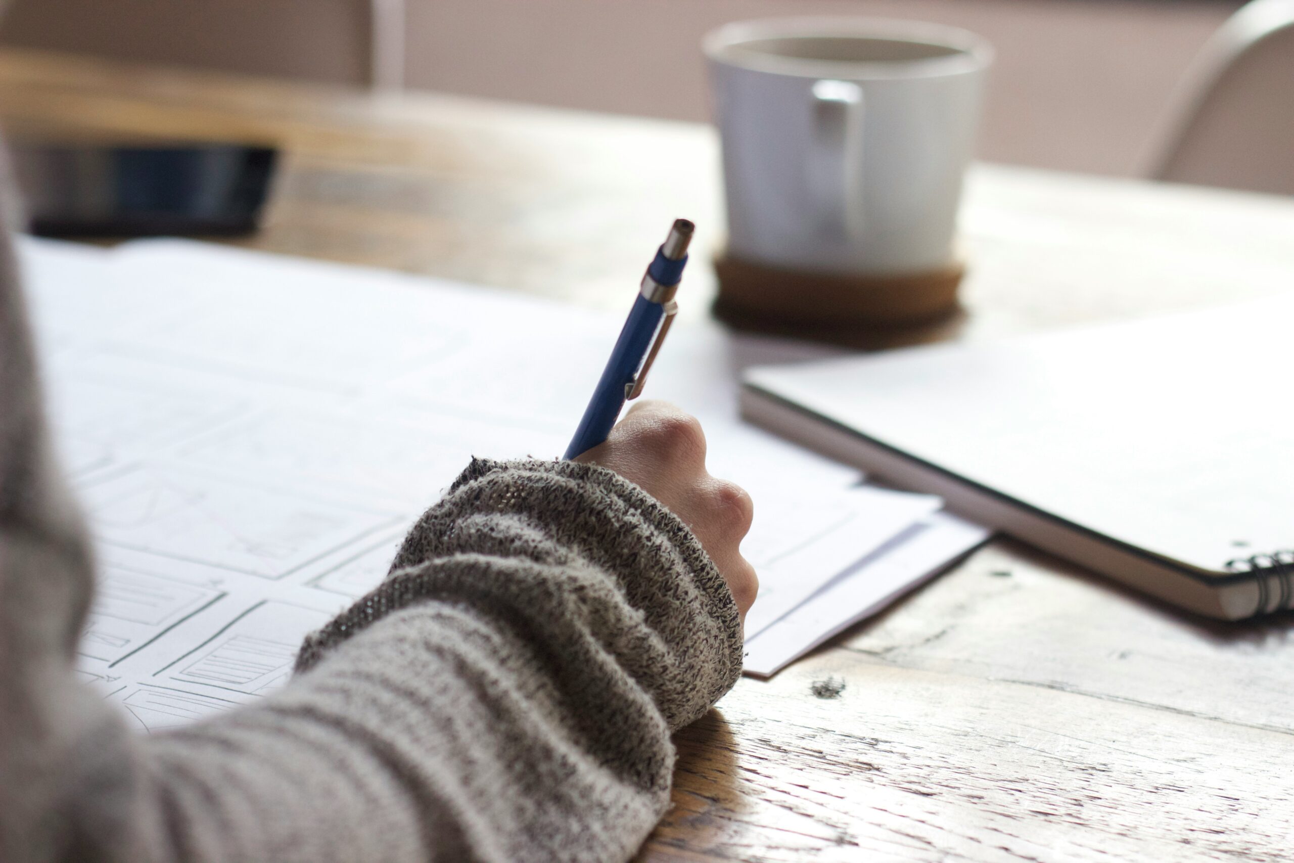 The arm of a person writing on paper at a desk